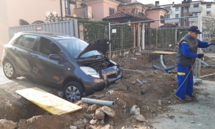 Esce con l'auto dal cancello condominiale e... cade nella buca di un cantiere