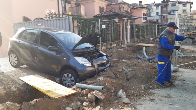 Esce con l’auto dal cancello condominiale e… cade nella buca di un cantiere
